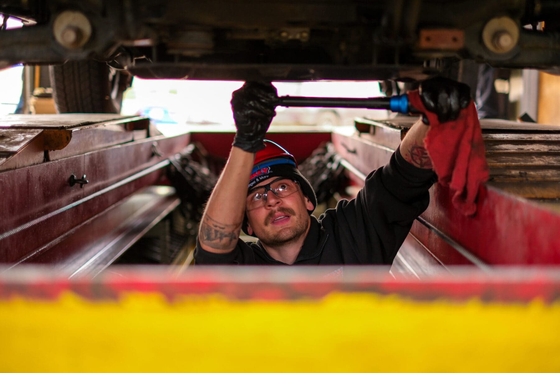 A Grease Monkey technician skillfully performing oil change on the underside of a car, ensuring quality auto service.